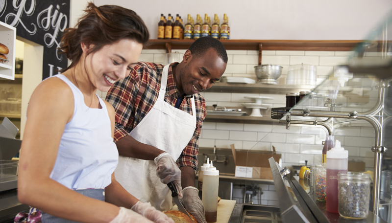 Happy couple working behind the counter at a sandwich bar