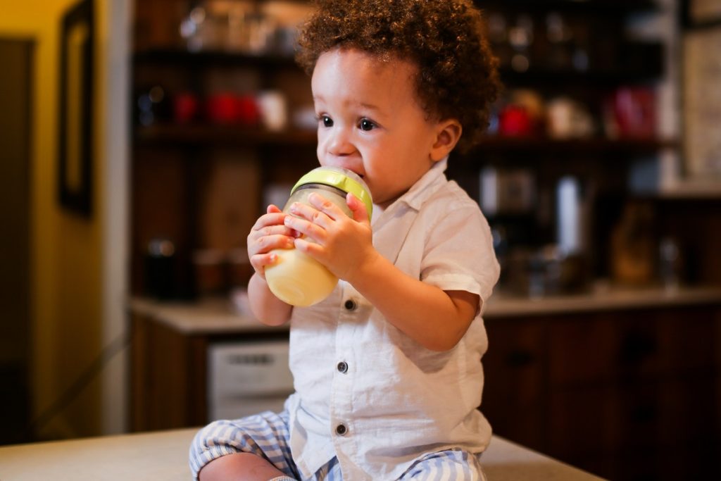 A child drinks milk. Proper food hygiene in early years settings is vital to his safety,