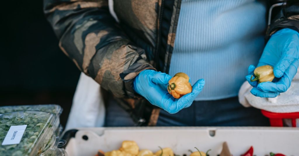 A man handles food with gloves, practicing good food hygiene.