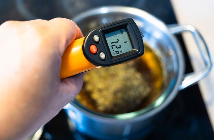 Somebody checking the temperature of some food in a sauce pan