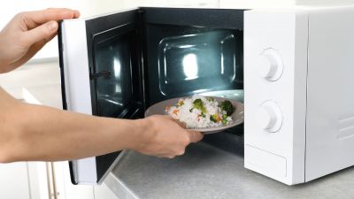 Somebody putting food into a microwave